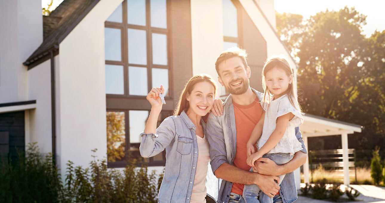 Urban Village. Family of three standing outdoors near house holding keys from new apartment in sunlight smiling cheerful Haus kaufen München